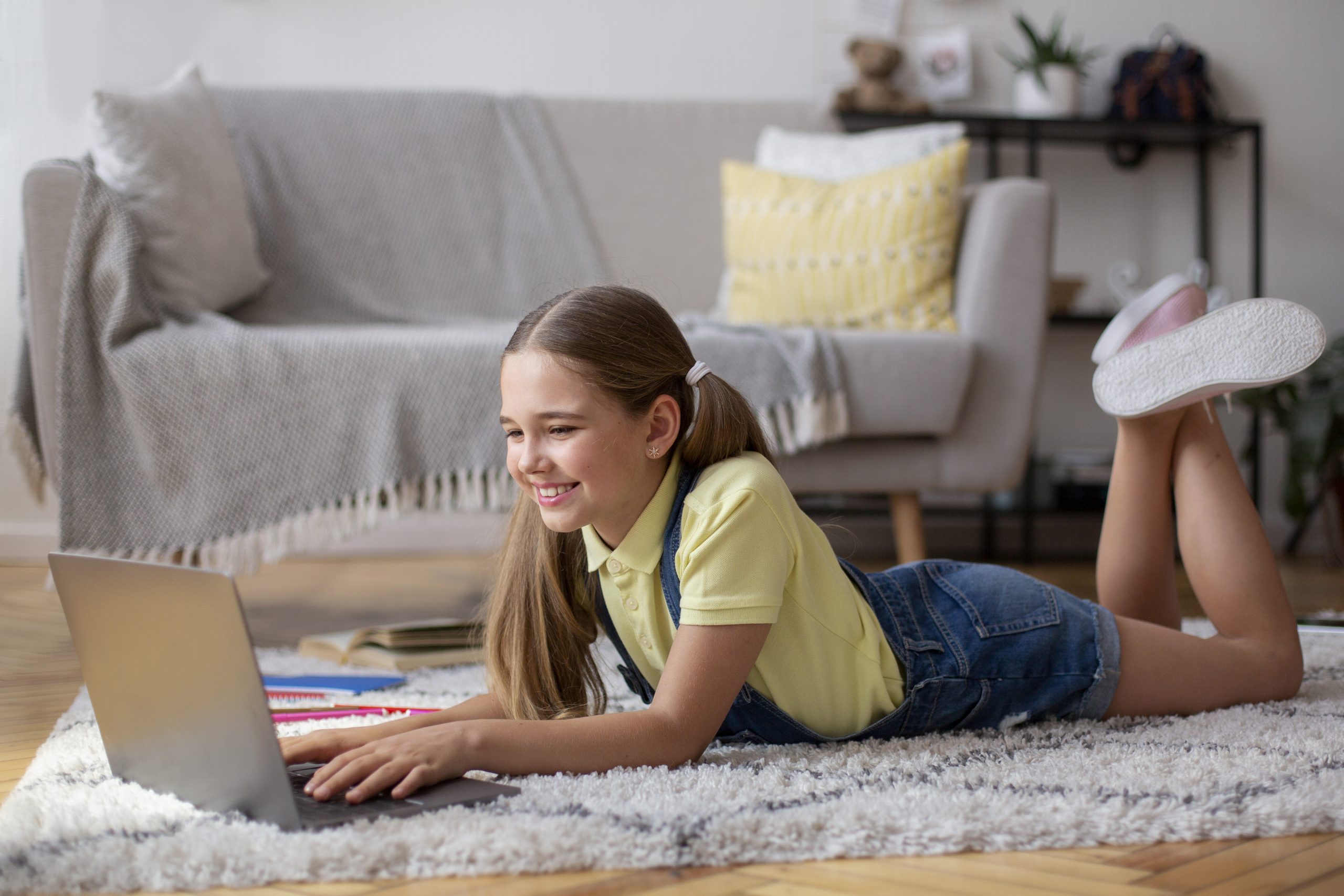 Girl lying on floor carpet and using pc