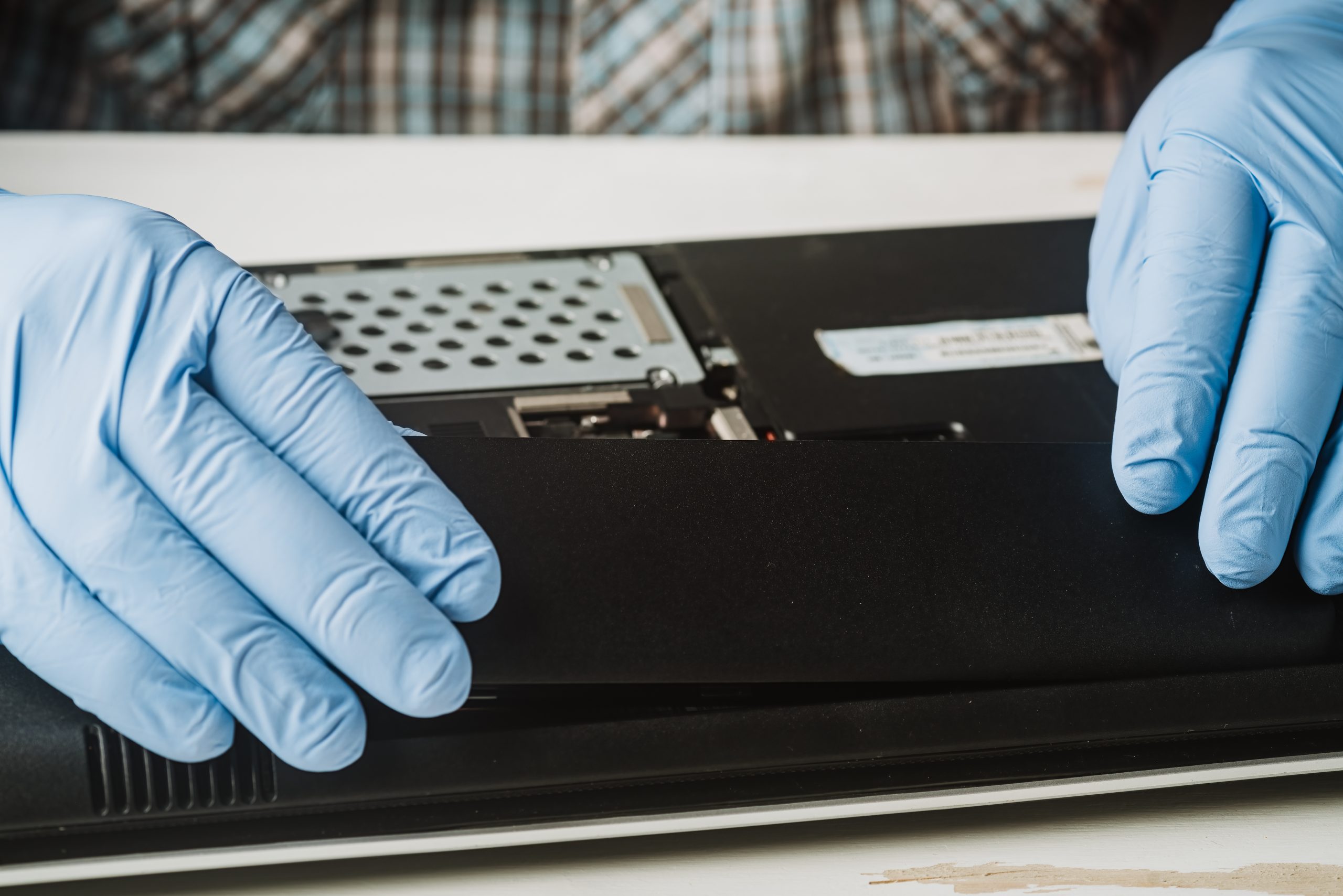 Hands of a man disassembling a laptop computer
